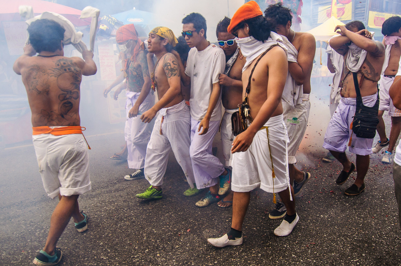 Группа носильщиков носилок в дыму. Вегетарианский фестиваль на Пхукете.